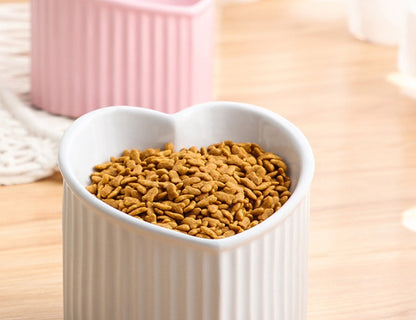 White ceramic pet bowl inclined mouth, heart-shaped design for cats and dogs, filled with pet kibble